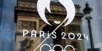 The Arc de Triomphe reflects in an official's store window for the Paris 2024 Summer Olympic and Paralympic Games in Paris on December 15, 2023. (Photo by Dimitar DILKOFF / AFP)